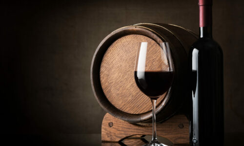 Red wine near wooden barrel on a brown background